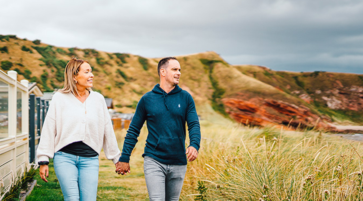 Couple holding hands and walking at Pease Bay