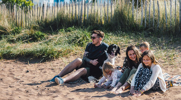 Family with a dog sitting on the beach 