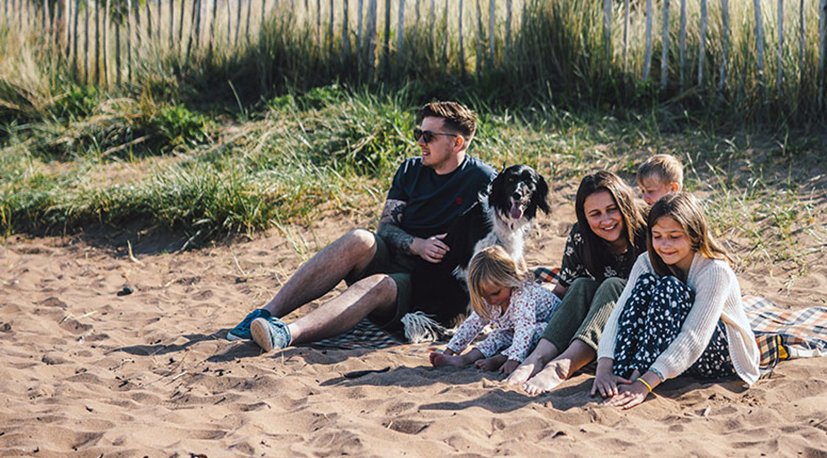 Family with a dog sitting on the beach