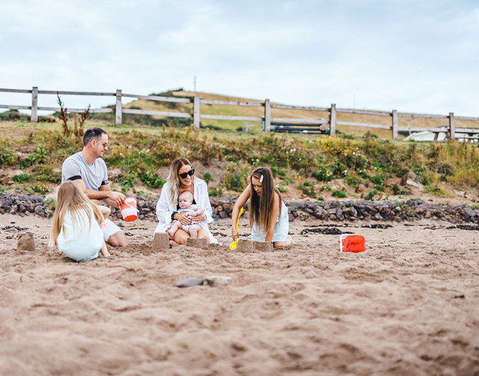 Family building sandcastles on the beach at Pease Bay