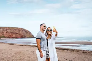 Couple taking a selfie on the beach at Pease Bay