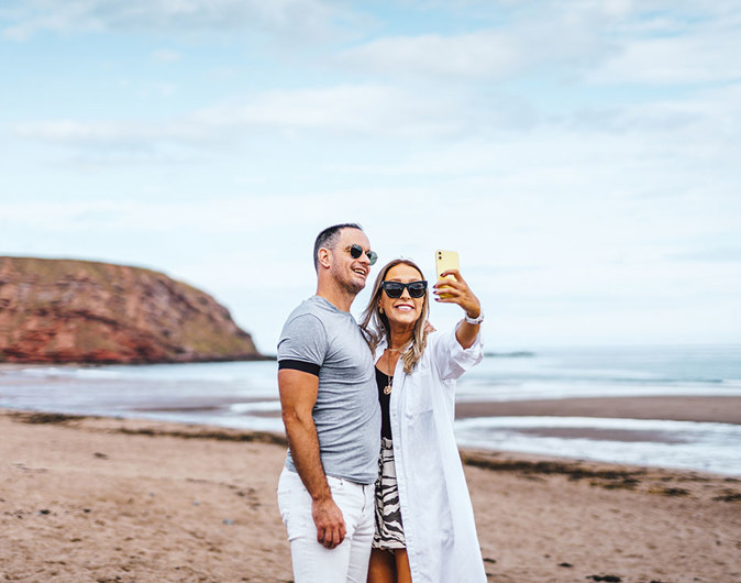 Couple taking a selfie on the beach at Pease Bay