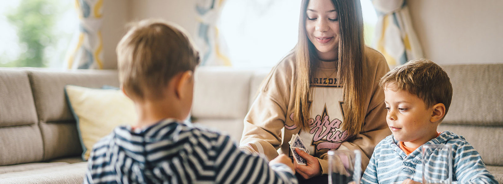 Children playing a card game in caravan accommodation at Coldingham Bay