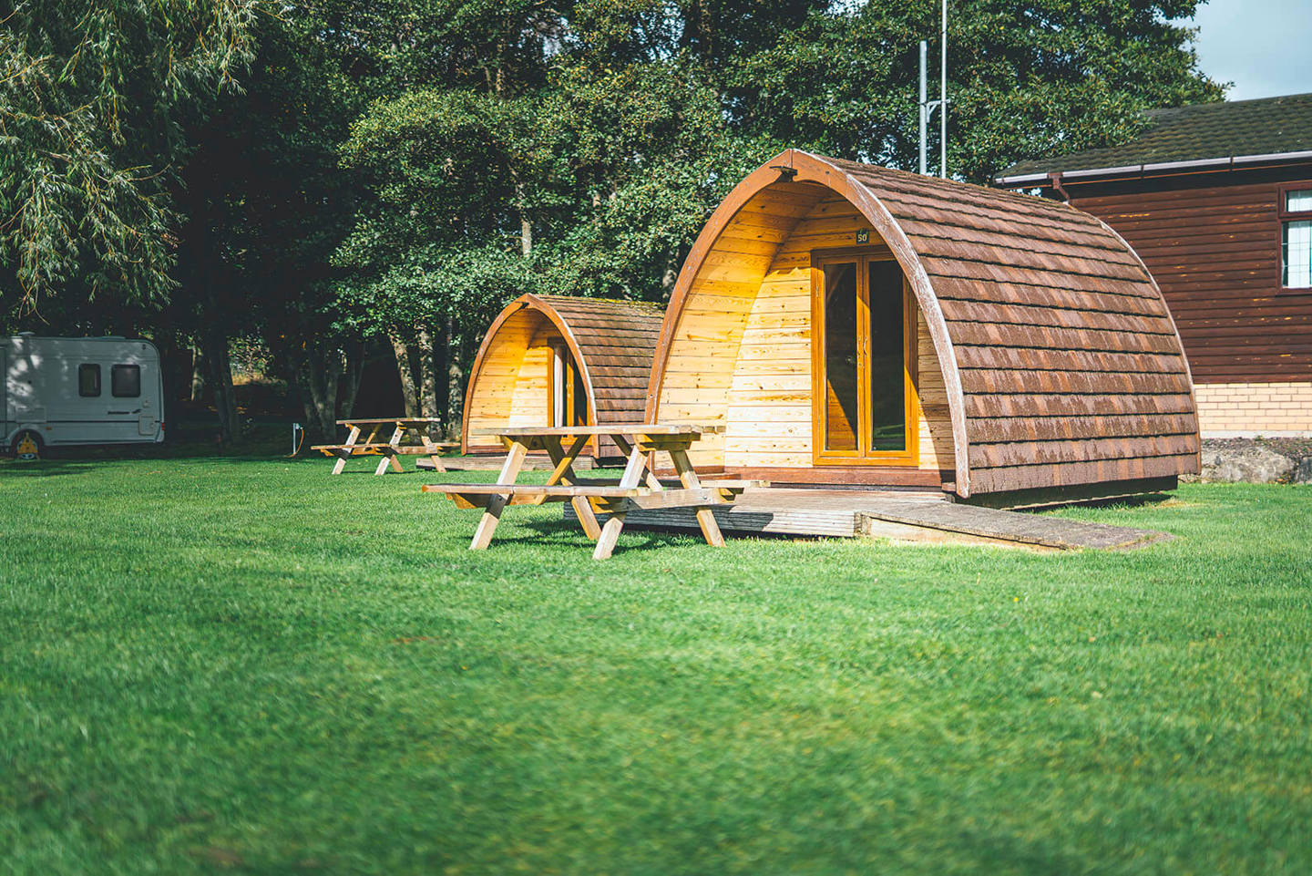 Camping pod accommodation with picnic benches on the grass 