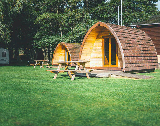 Camping pod accommodation with picnic benches on the grass