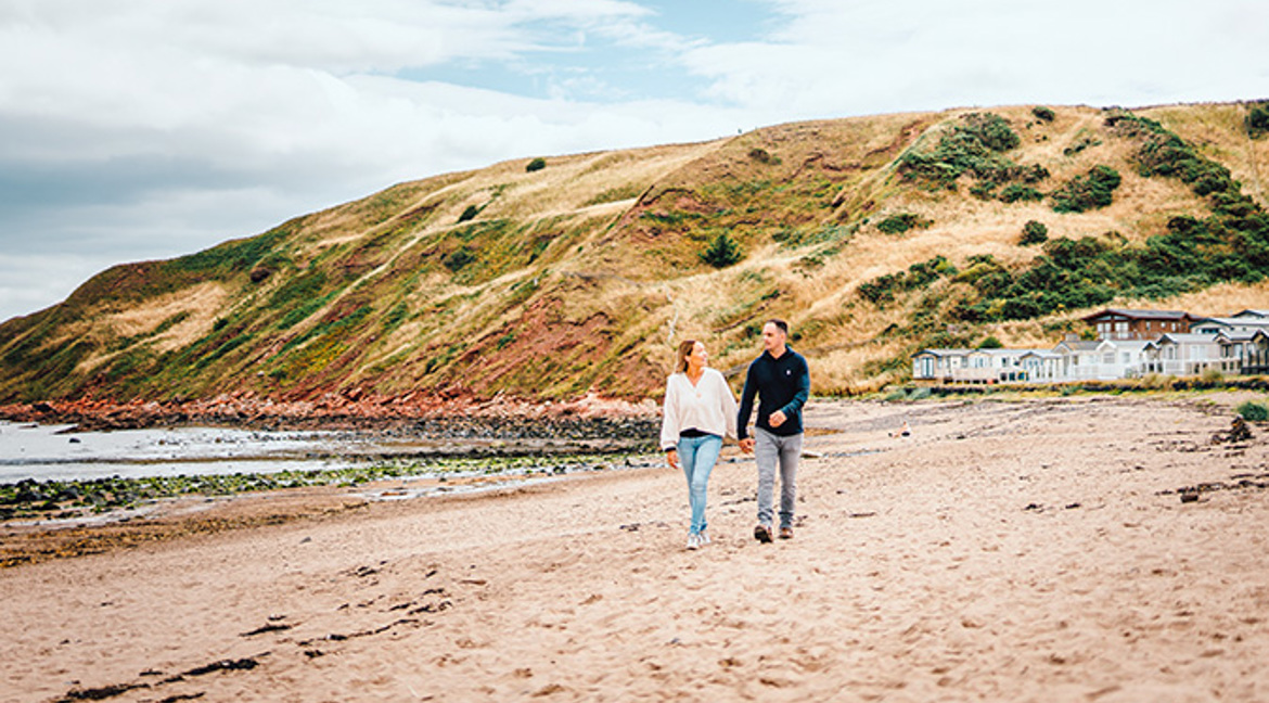 Couple walking along the beach at Pease Bay