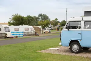 Blue and white touring vans and motorhomes in a touring field