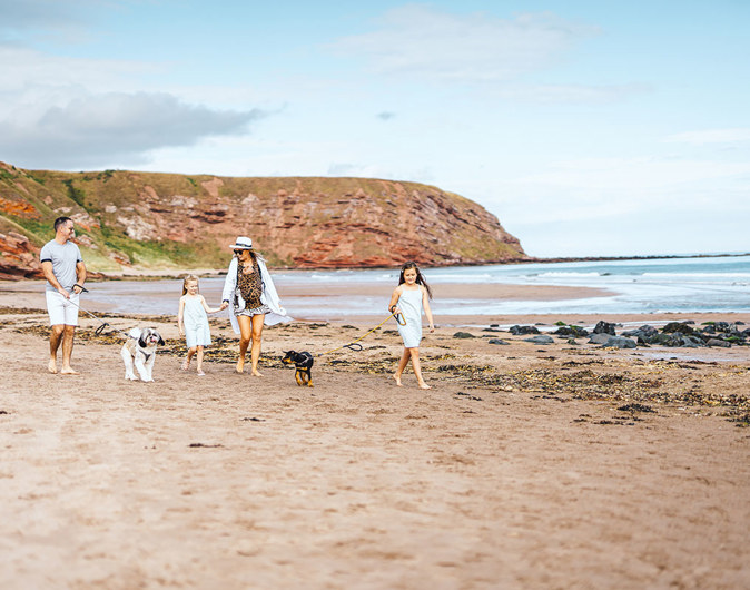 Family with dogs walking on the beach at Pease Bay
