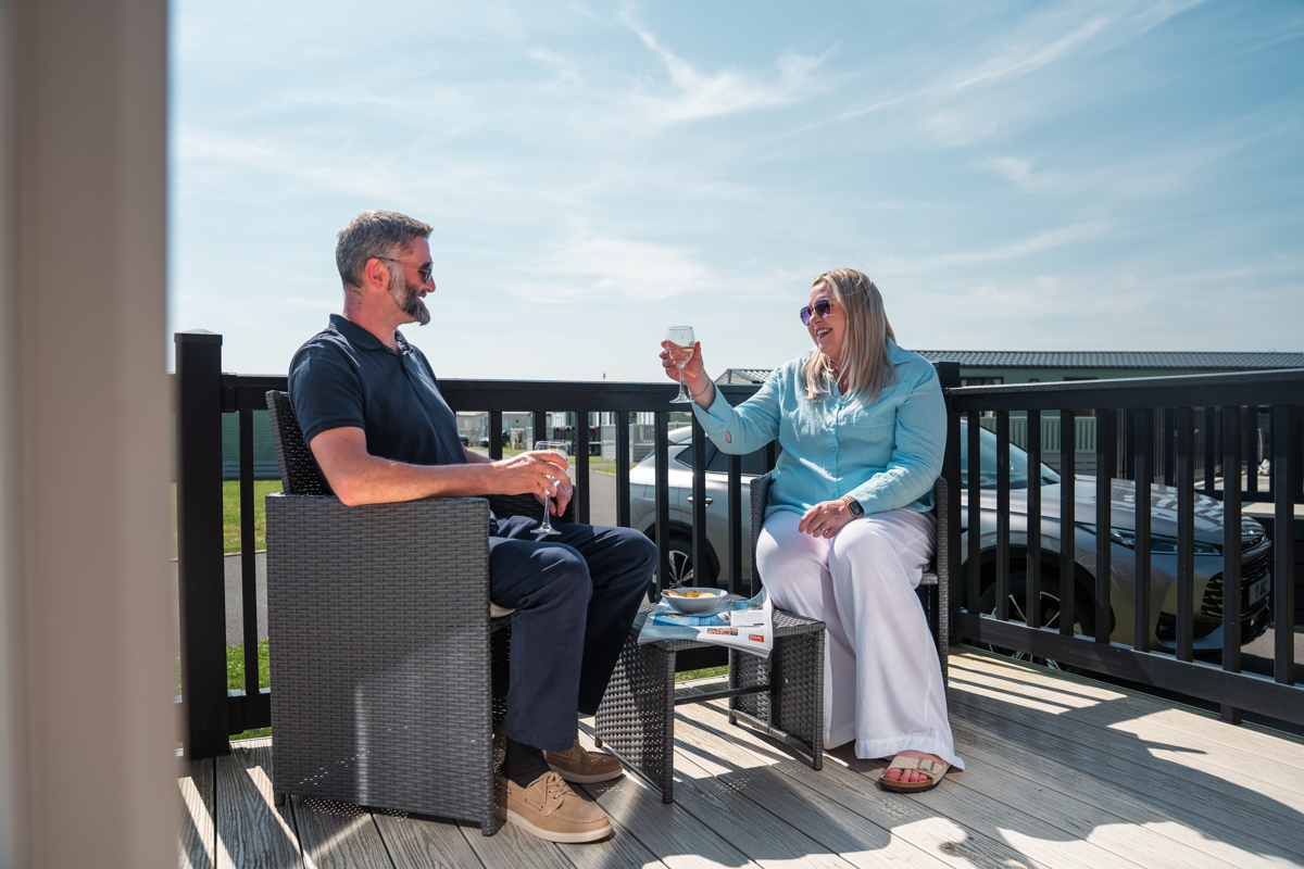 Couple with drinks on lodge decking